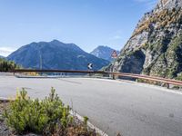 a man on a bike passing by an upside down road bridge in the mountains above a valley