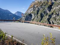 a man on a bike passing by an upside down road bridge in the mountains above a valley
