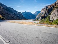 the curved road on the side of a mountainside with trees in front of it