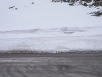 a snow covered hill on an empty road in winter time and a woman is riding her bike