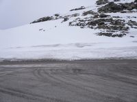 a snow covered hill on an empty road in winter time and a woman is riding her bike