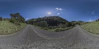 the view from a fisheye lens looking up at a road with mountains in the background