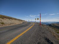 a mountain road with a warning sign and two yellow caution signs on either side of the street