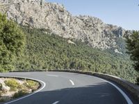 the curved roadway with trees, mountains and bushes is empty and empty of people on it