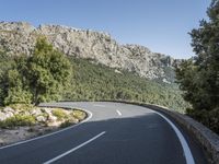 the curved roadway with trees, mountains and bushes is empty and empty of people on it