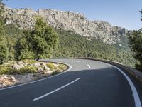 the curved roadway with trees, mountains and bushes is empty and empty of people on it