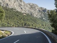 the curved roadway with trees, mountains and bushes is empty and empty of people on it