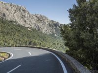 the curved roadway with trees, mountains and bushes is empty and empty of people on it