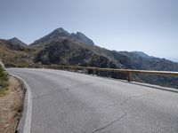 a large motorcycle is riding down an empty road over a mountain side, near the water