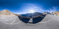 a 360 - view photograph of a road in the mountains near a snow capped mountain