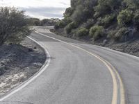 a guy is riding his skateboard down the road in a hilly area on his skateboard