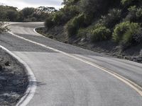 a guy is riding his skateboard down the road in a hilly area on his skateboard