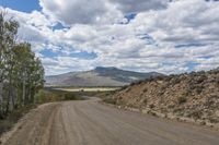 Mountain Road through Rural Landscape with Tree and Clouds