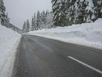 a snowy road in the winter with trees and snow on both sides of it and trees covered in snow