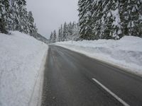 a snowy road in the winter with trees and snow on both sides of it and trees covered in snow