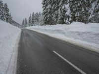 a snowy road in the winter with trees and snow on both sides of it and trees covered in snow