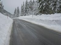 a snowy road in the winter with trees and snow on both sides of it and trees covered in snow
