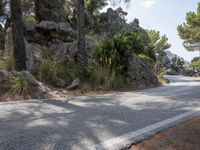 a black motorcycle is stopped on the side of a mountain road and is surrounded by rocks