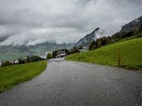 the landscape is covered with many different views and clouds, and a winding road leads towards some mountains and a small lake
