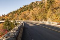 a scenic view of a bridge across a valley near trees and rocks on the side of the road