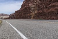 a mountain road with a cliff behind it and no traffic as if going by or riding