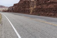 a mountain road with a cliff behind it and no traffic as if going by or riding