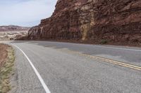 a mountain road with a cliff behind it and no traffic as if going by or riding