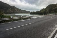 a scenic highway with a river and mountains in the distance and a bridge spanning the width of the road