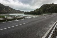 a scenic highway with a river and mountains in the distance and a bridge spanning the width of the road