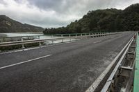 a scenic highway with a river and mountains in the distance and a bridge spanning the width of the road