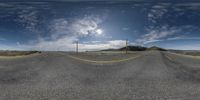 two intersecting roads with a few cars going by on it and a sky background and mountain