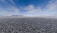 a vast view of a mountain and sand plain and mountains with blue skies above them