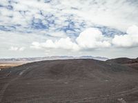 the mountain with dirt is full of dirt and clouds above the mountainside on a partly cloudy day