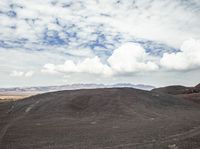 the mountain with dirt is full of dirt and clouds above the mountainside on a partly cloudy day