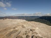 person with a backpack looking out over a rocky area at the mountains below them and an expansive river