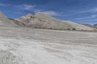 a motorcycle on dirt road with desert hills behind it in the background, blue sky and clouds