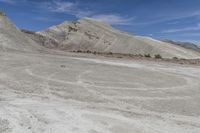 a motorcycle on dirt road with desert hills behind it in the background, blue sky and clouds