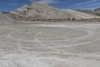 a motorcycle on dirt road with desert hills behind it in the background, blue sky and clouds