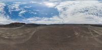 a mountain top with sand dunes and a cloudy sky in the background with some clouds