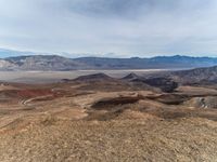 a person on a motorcycle rides down a mountain top to the mountains behind them,