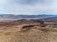 a person on a motorcycle rides down a mountain top to the mountains behind them,