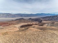 a person on a motorcycle rides down a mountain top to the mountains behind them,