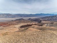 a person on a motorcycle rides down a mountain top to the mountains behind them,