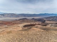 a person on a motorcycle rides down a mountain top to the mountains behind them,