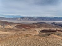 a person on a motorcycle rides down a mountain top to the mountains behind them,