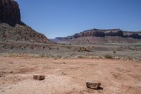 a dirt road through a desert plain with a mountain behind it and a clear blue sky in the background