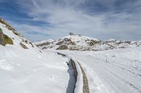 a snow covered mountain with tracks in the snow on a trail leading to a snowy hill