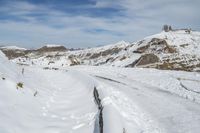 a snow covered mountain with tracks in the snow on a trail leading to a snowy hill