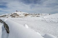 a snow covered mountain with tracks in the snow on a trail leading to a snowy hill