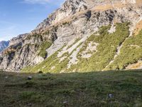 a man standing in a valley with the mountains in the background taking a picture of his dog